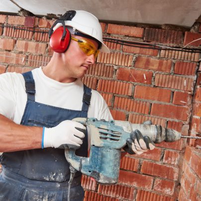 man using a drill on a construction site